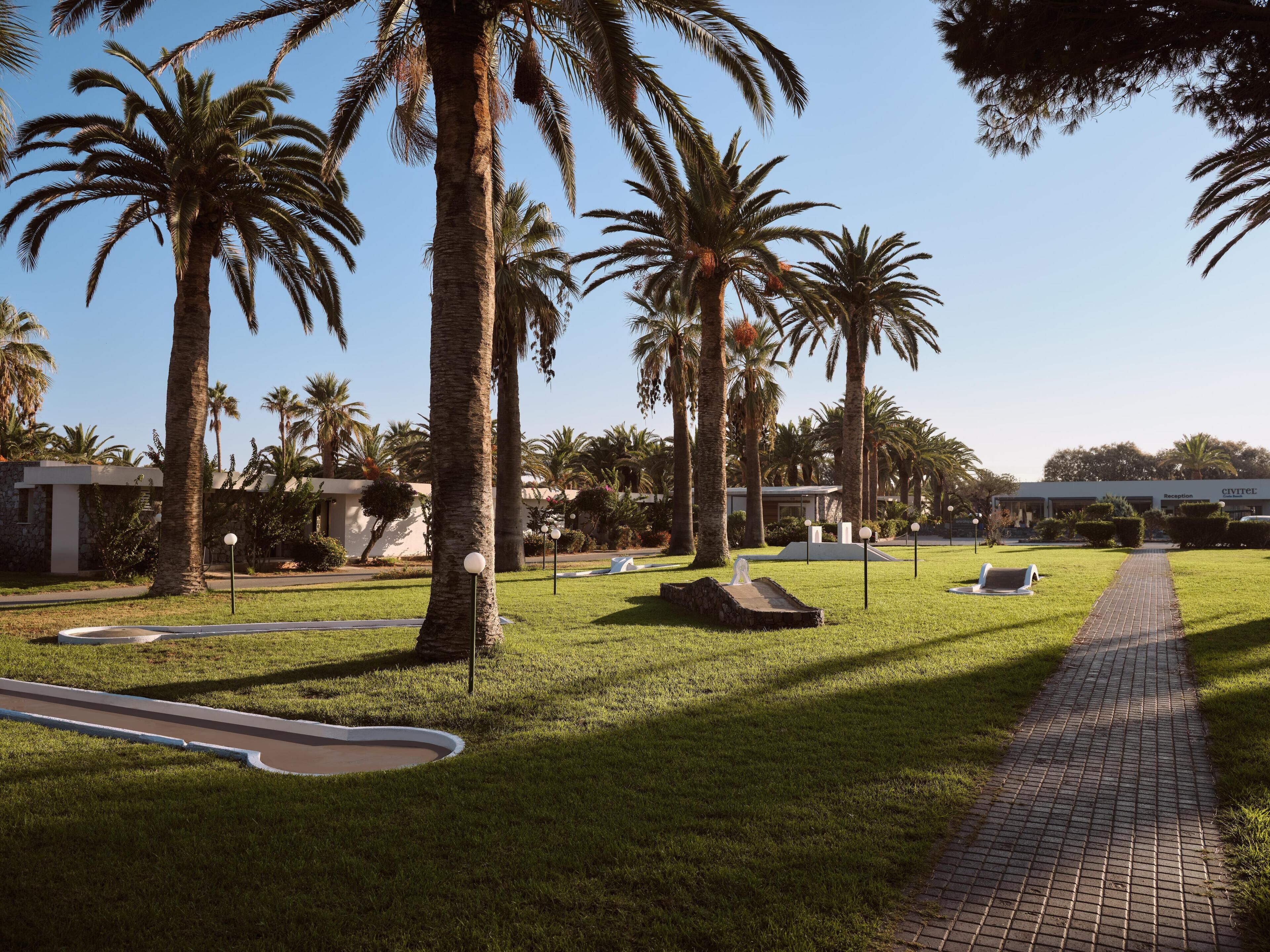 A well-maintained outdoor area with palm trees, a paved walkway, and a reception building labeled "CIVITEL".