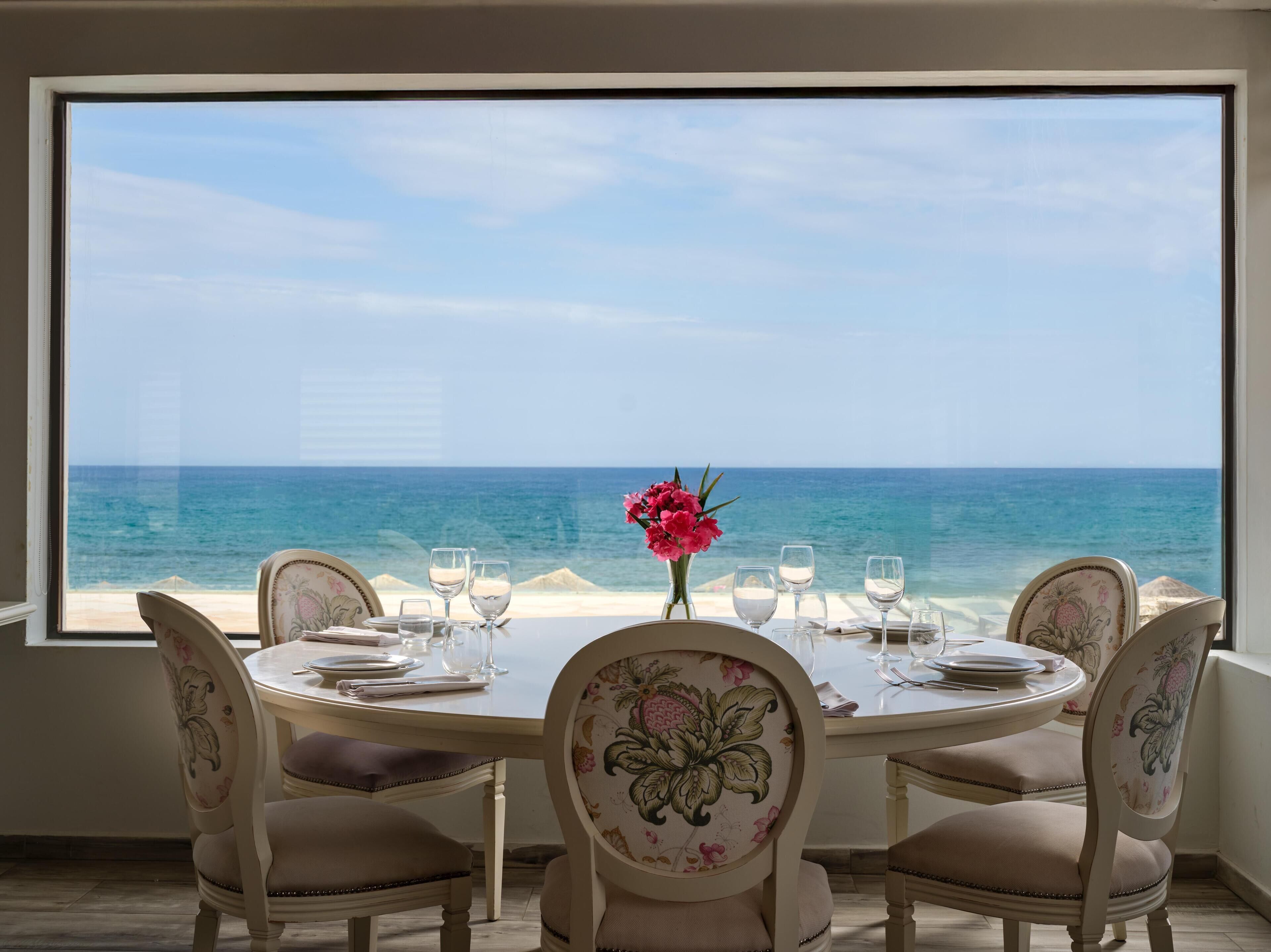 Une table à manger avec des chaises et une vue sur l’océan.