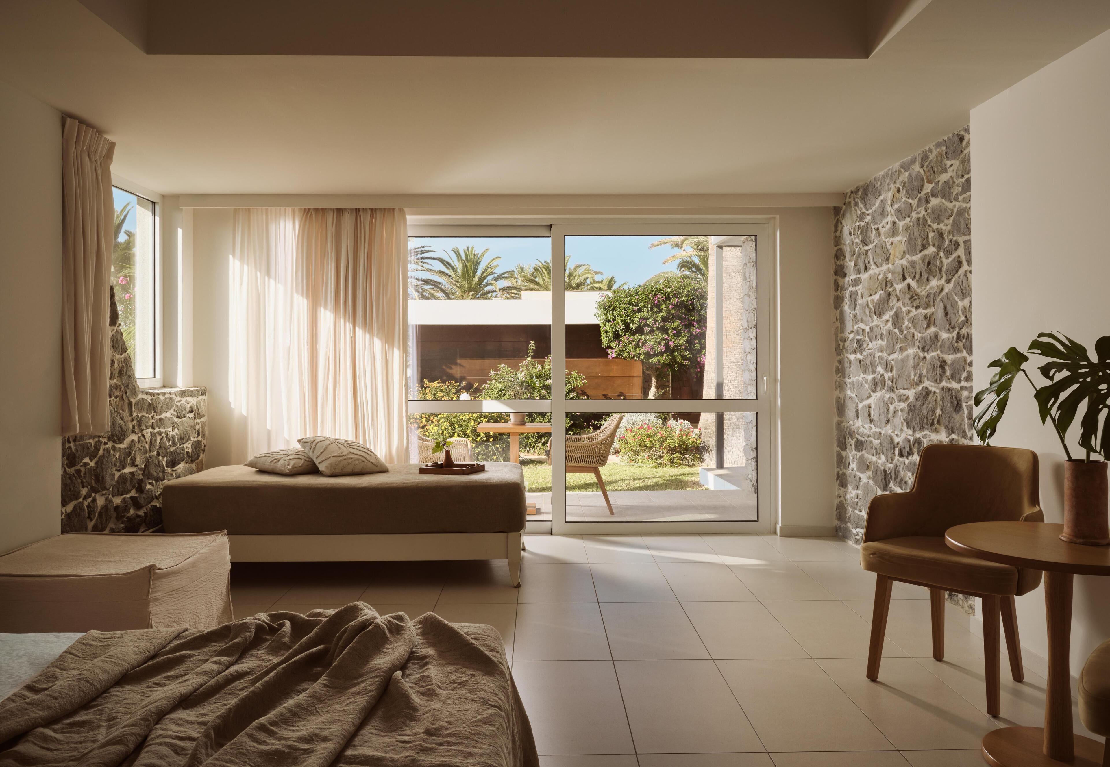 Un dormitorio moderno con una cama grande, un rincón de descanso y vistas al exterior.