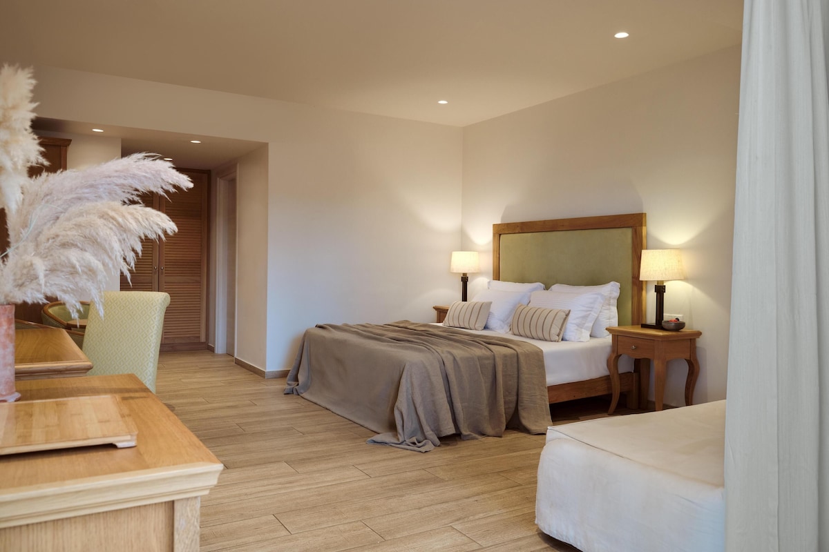 A hotel room with a bed, bedside tables, a lamp, a chair, and a wooden floor.
