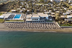 Vista aérea de um resort com uma piscina grande, vários edifícios e uma área de praia.