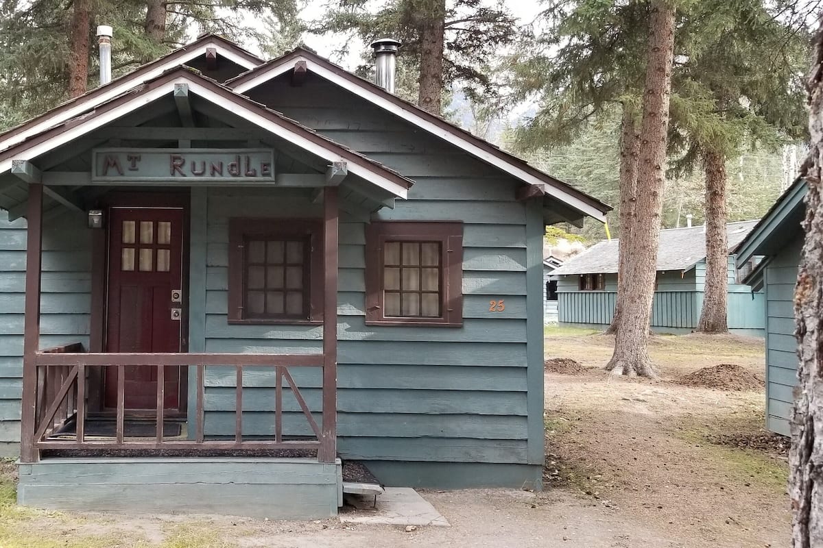 A small, single-story cabin with a porch, labeled "Mt Rundle," surrounded by trees.