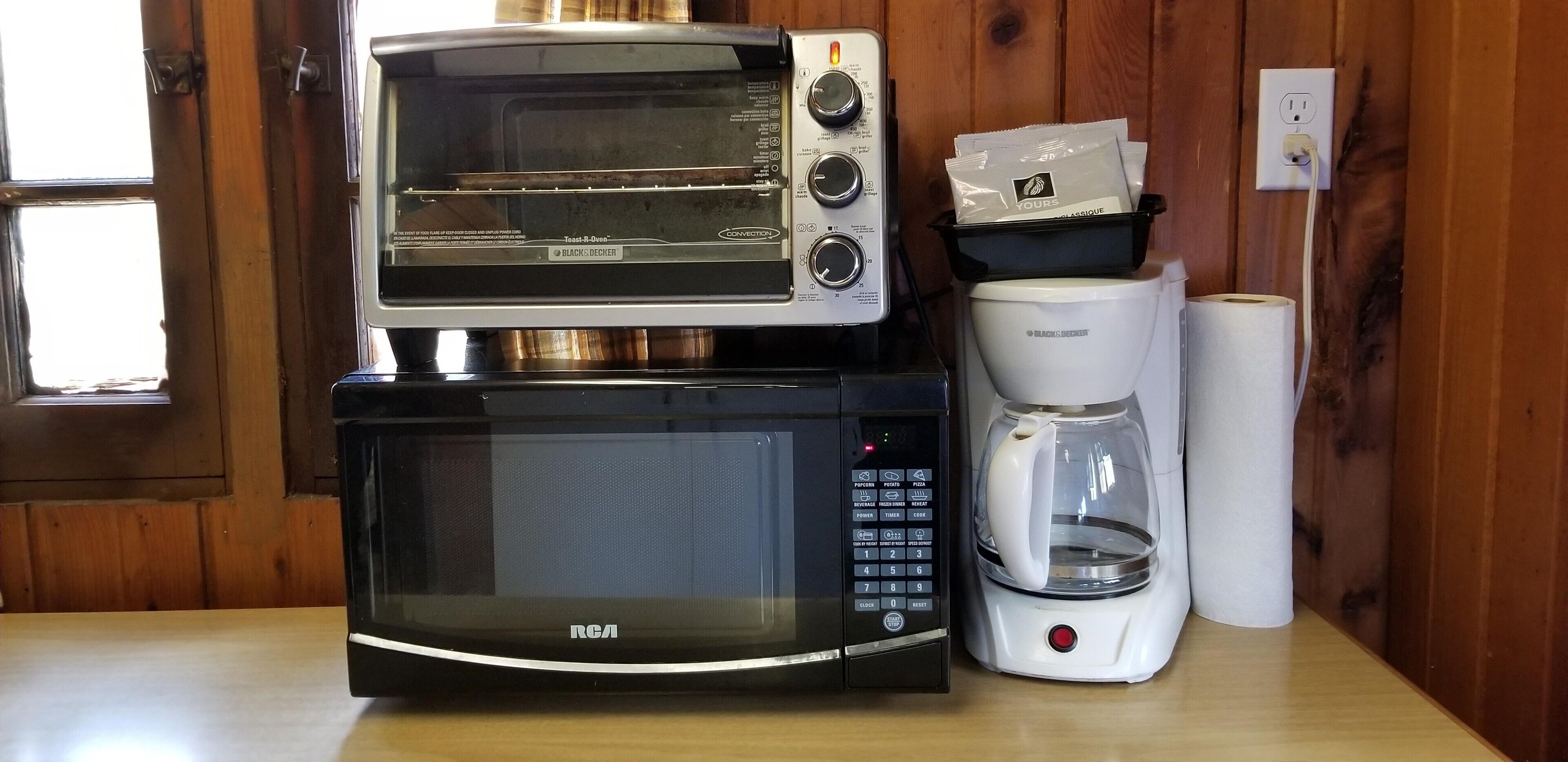 A kitchen with a toaster oven, a microwave, and a coffee maker on a wooden countertop.