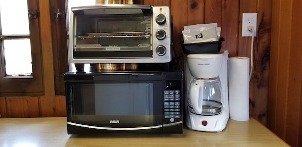 A kitchen with a toaster oven, a microwave, and a coffee maker on a wooden countertop.
