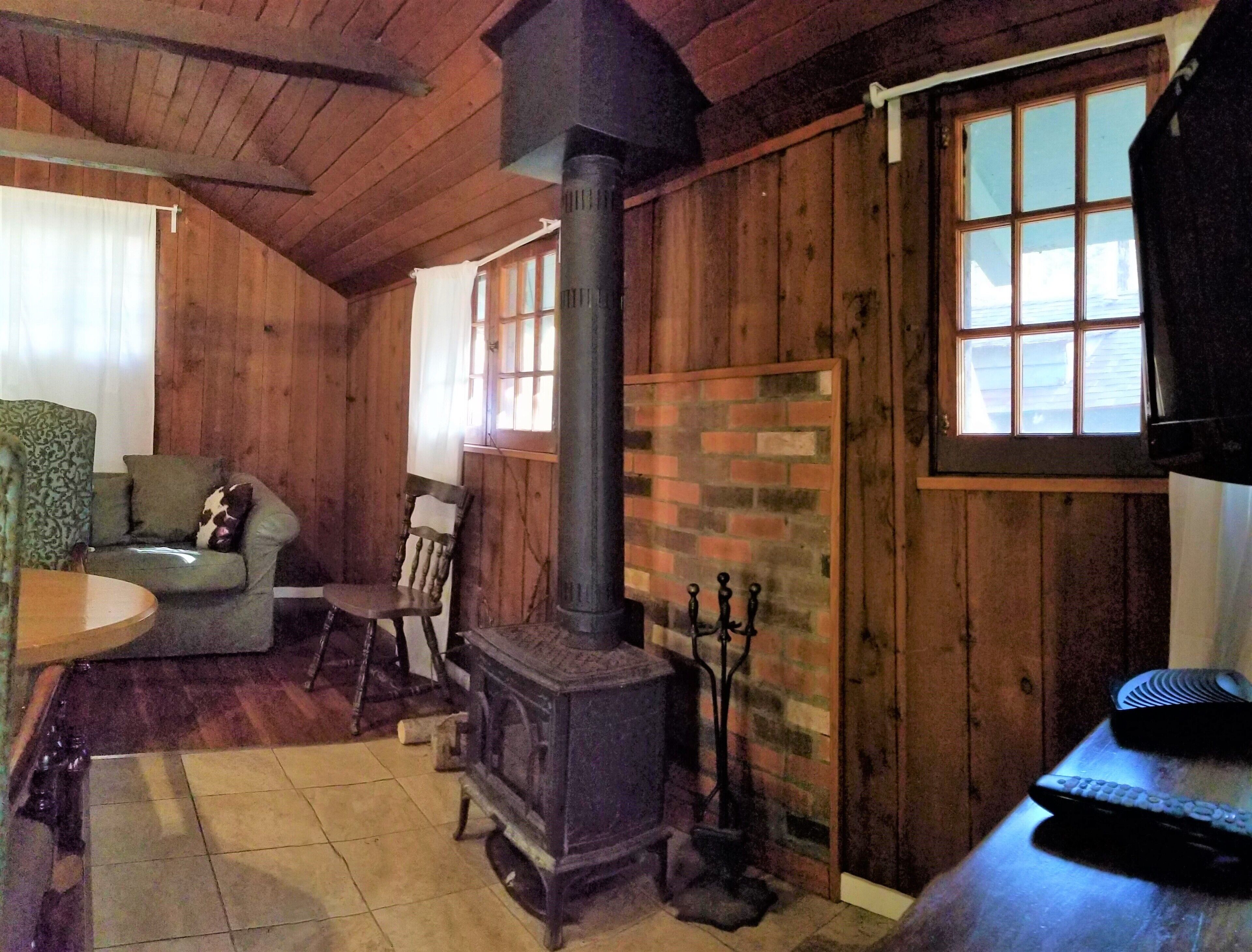 Una habitación acogedora con detalles de madera, chimenea, una mesa de comedor y un ventanal.