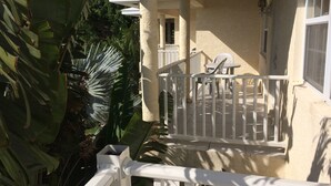 A balcony with white railings, a table, and chairs. - Sapphire Garden Townhouses (George Town)