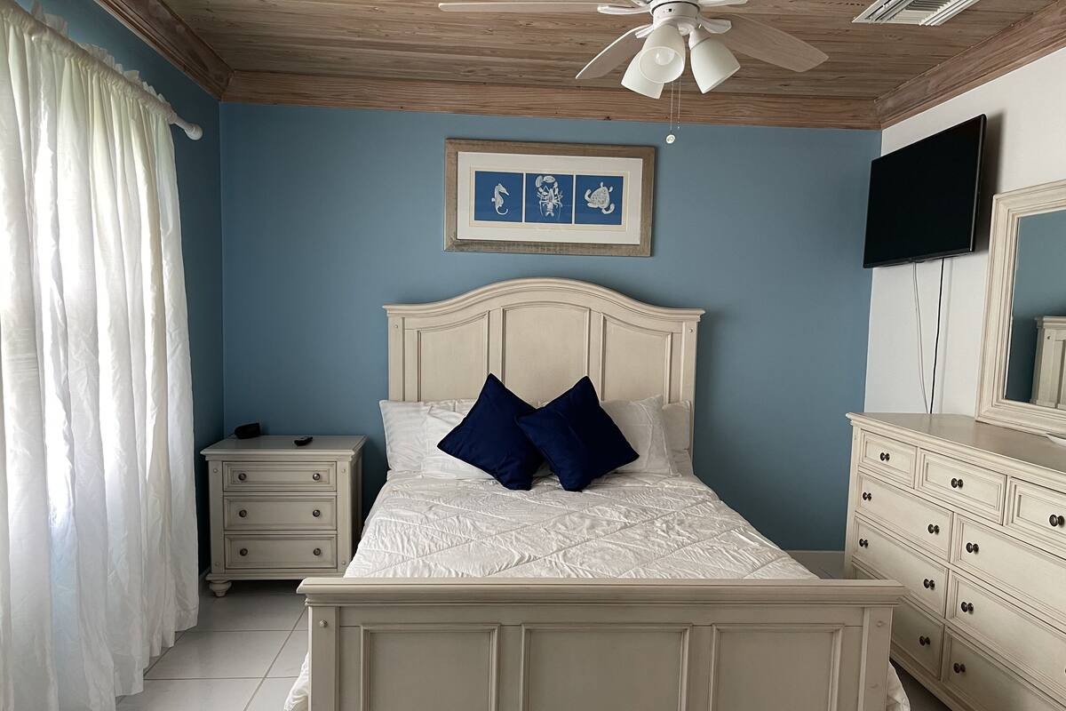 A bedroom with a bed, nightstand, dresser, and a ceiling fan.