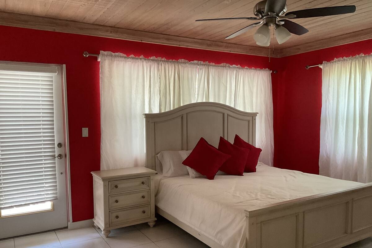 A bedroom with a bed, nightstand, and a ceiling fan.