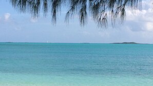 A beach with clear turquoise water, sandy shore, and distant land. - Sapphire Garden Townhouses (George Town)