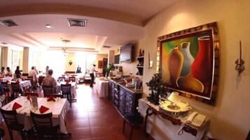Un restaurante amplio con numerosas mesas y sillas, una barra con un teléfono y un cuadro grande en la pared.