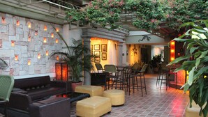 Une terrasse extérieure avec des murs en pierre, des sièges confortables et des plantes en pot.