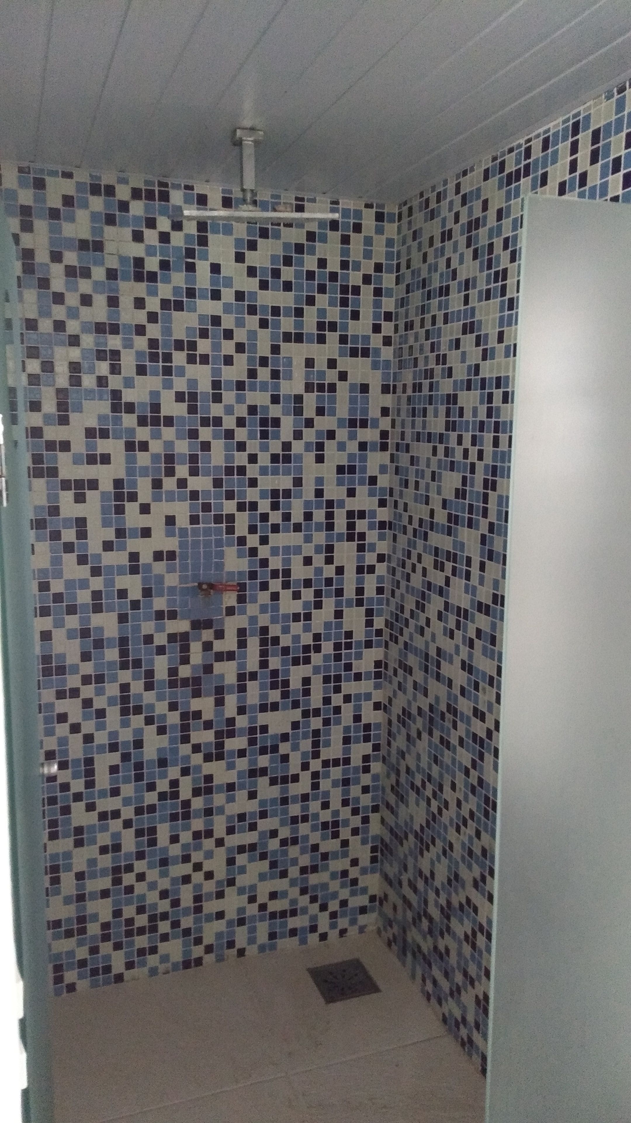 Een kleine badkamer met betegelde wanden en een douchegedeelte.