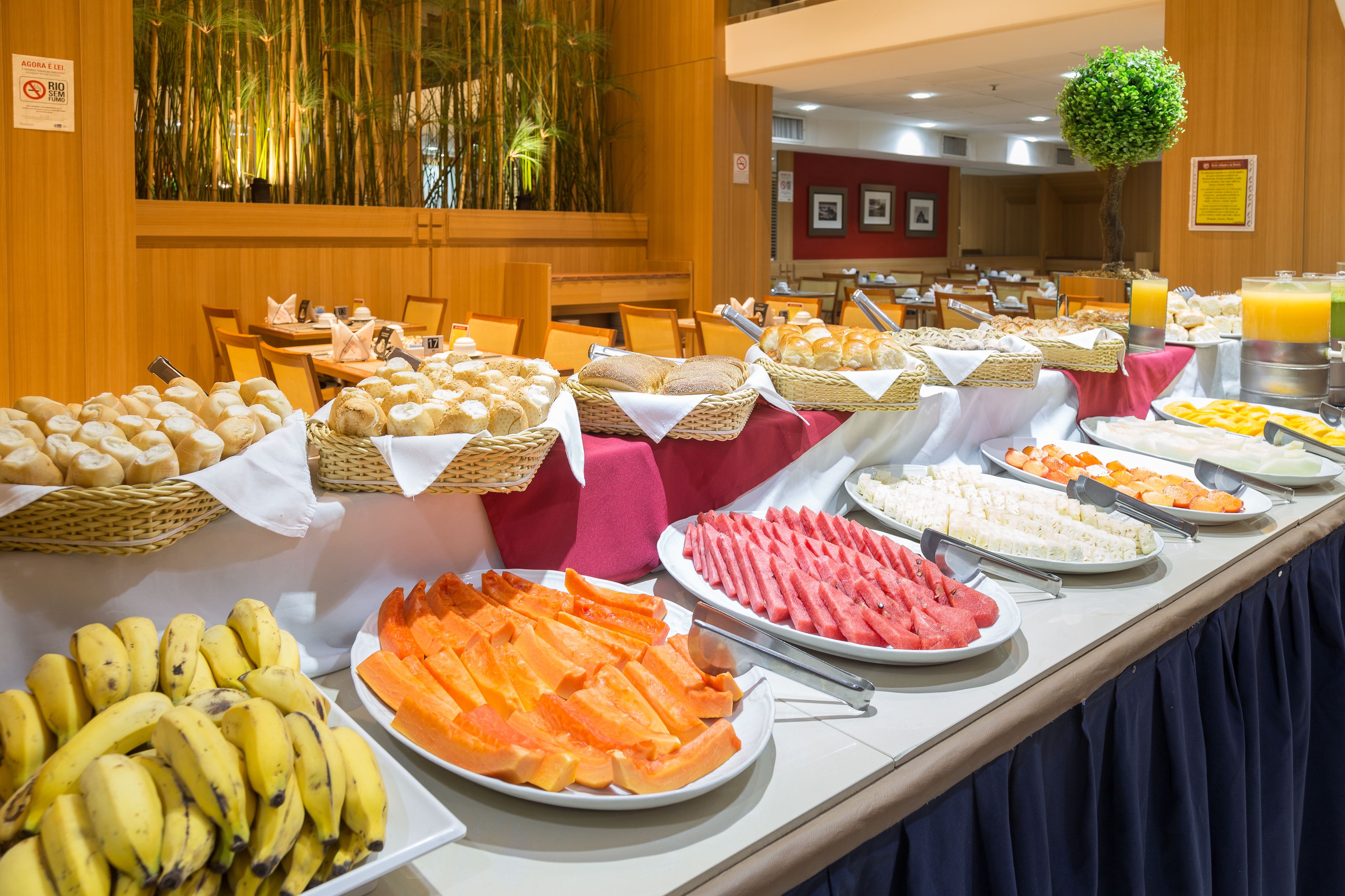 A buffet with various food items including fruits, bread, and pastries.