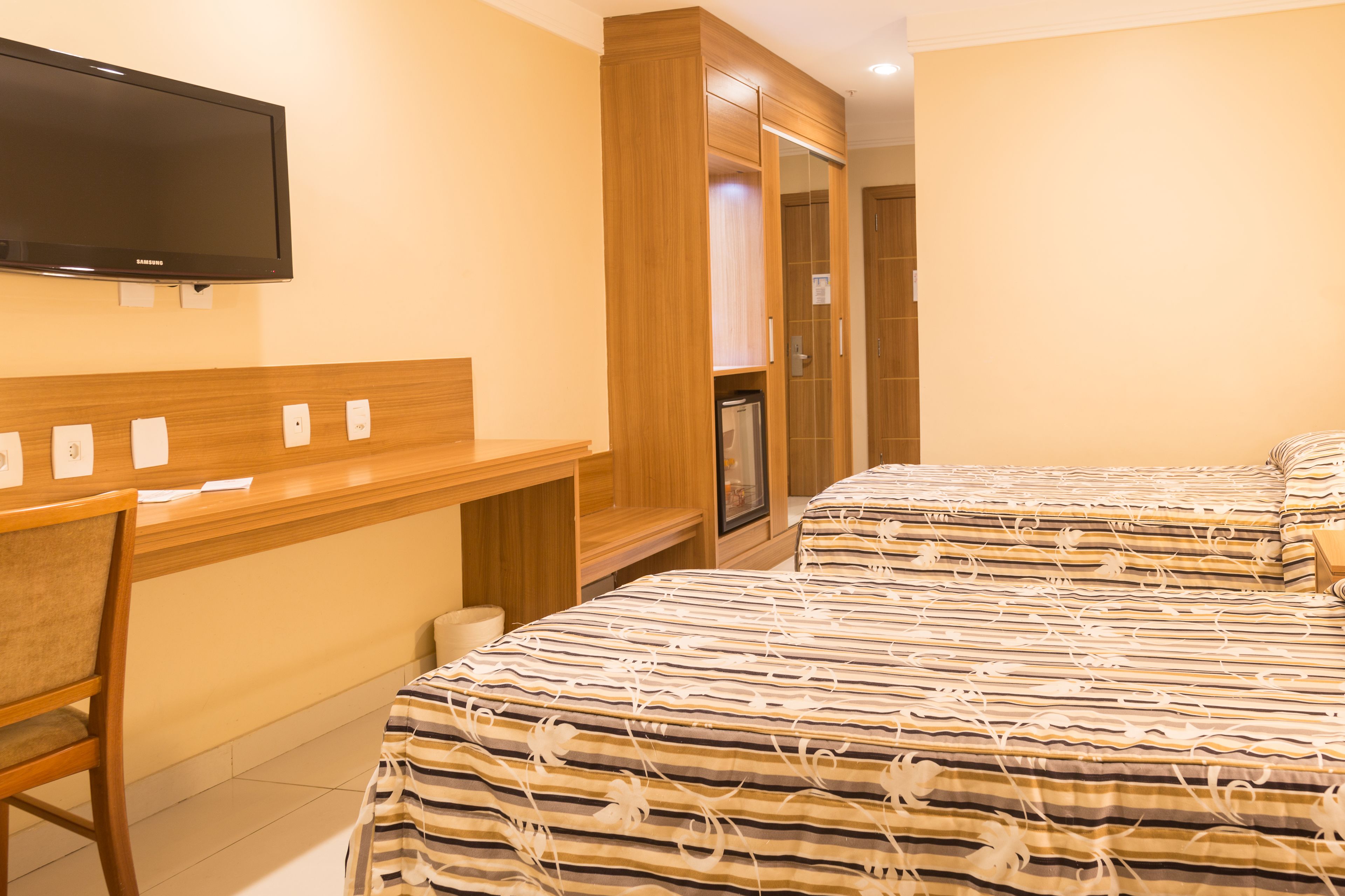 Une chambre d’hôtel équipée d’un lit, d’un bureau, d’une chaise, d’une télévision et d’une armoire.