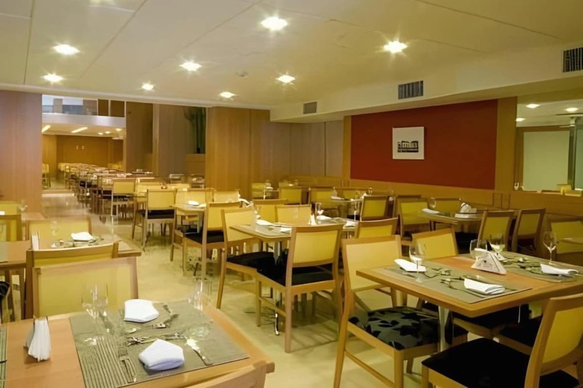 Ein Hotelrestaurant mit mehreren Tischen und Stühlen, die in Reihen angeordnet sind.