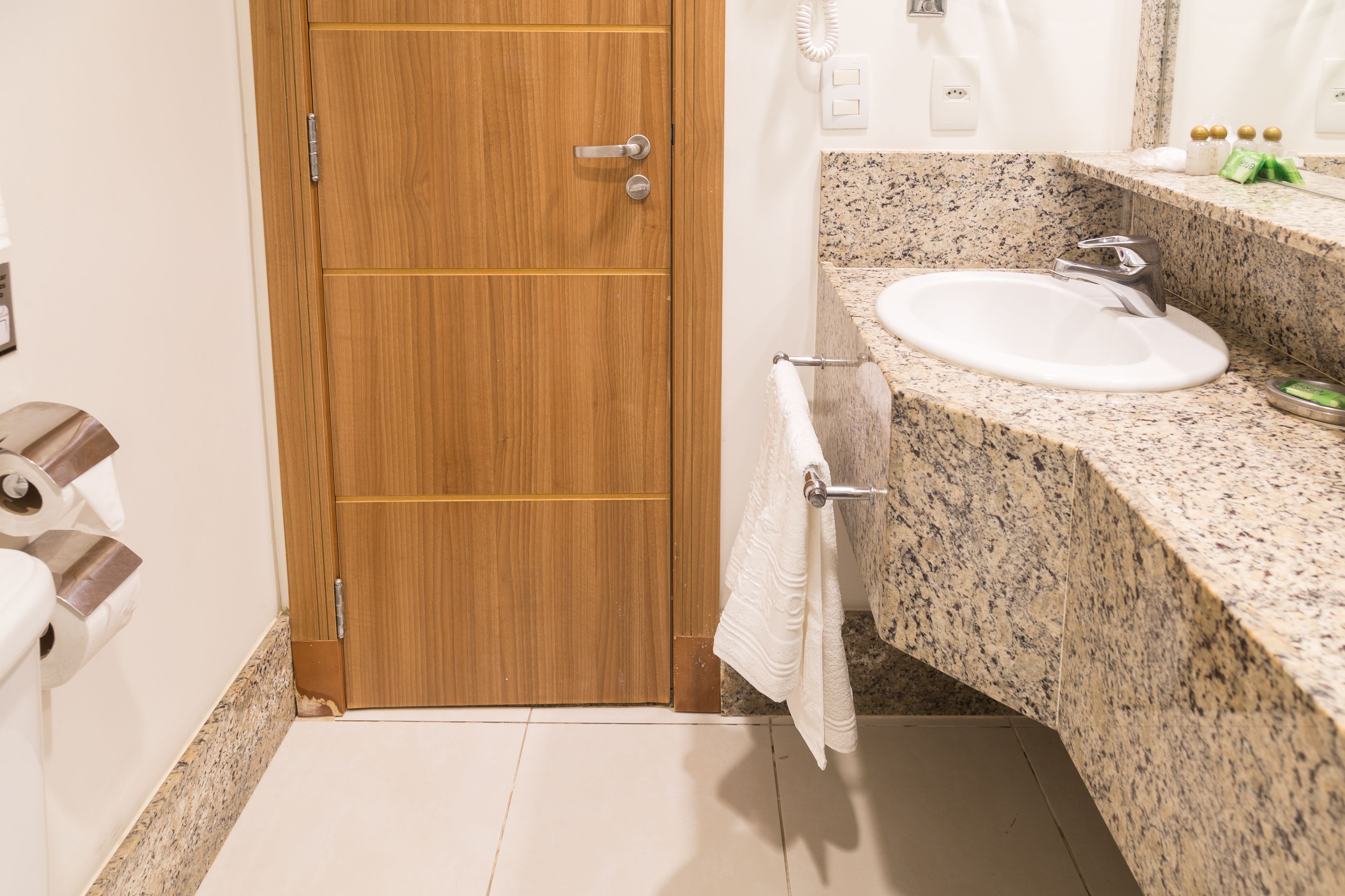 Un baño con puerta de madera, un lavabo y un perchero para toallas.
