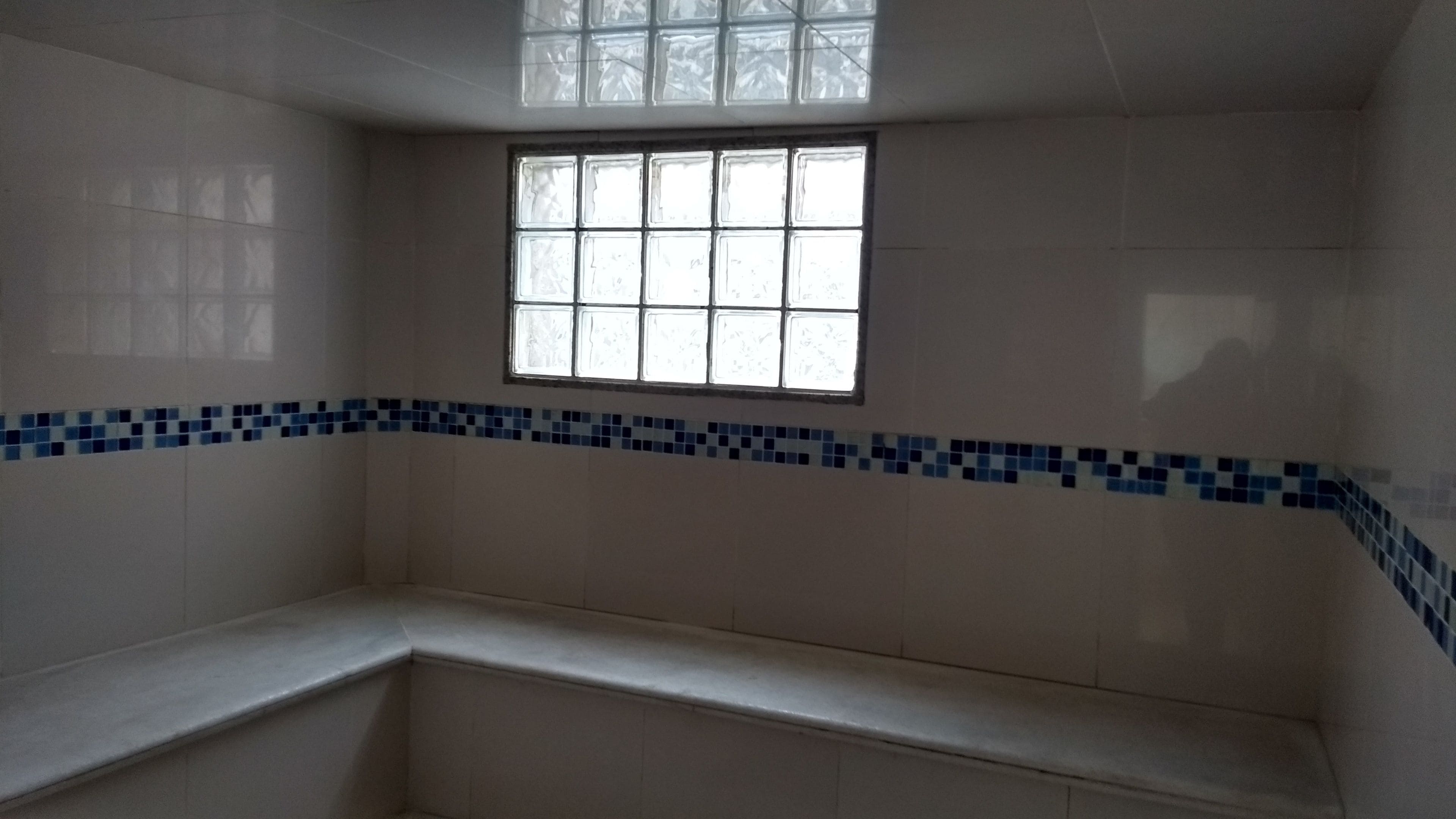 Ein Badezimmer mit Fenster, gefliesten Wänden und einer Sitzbank.