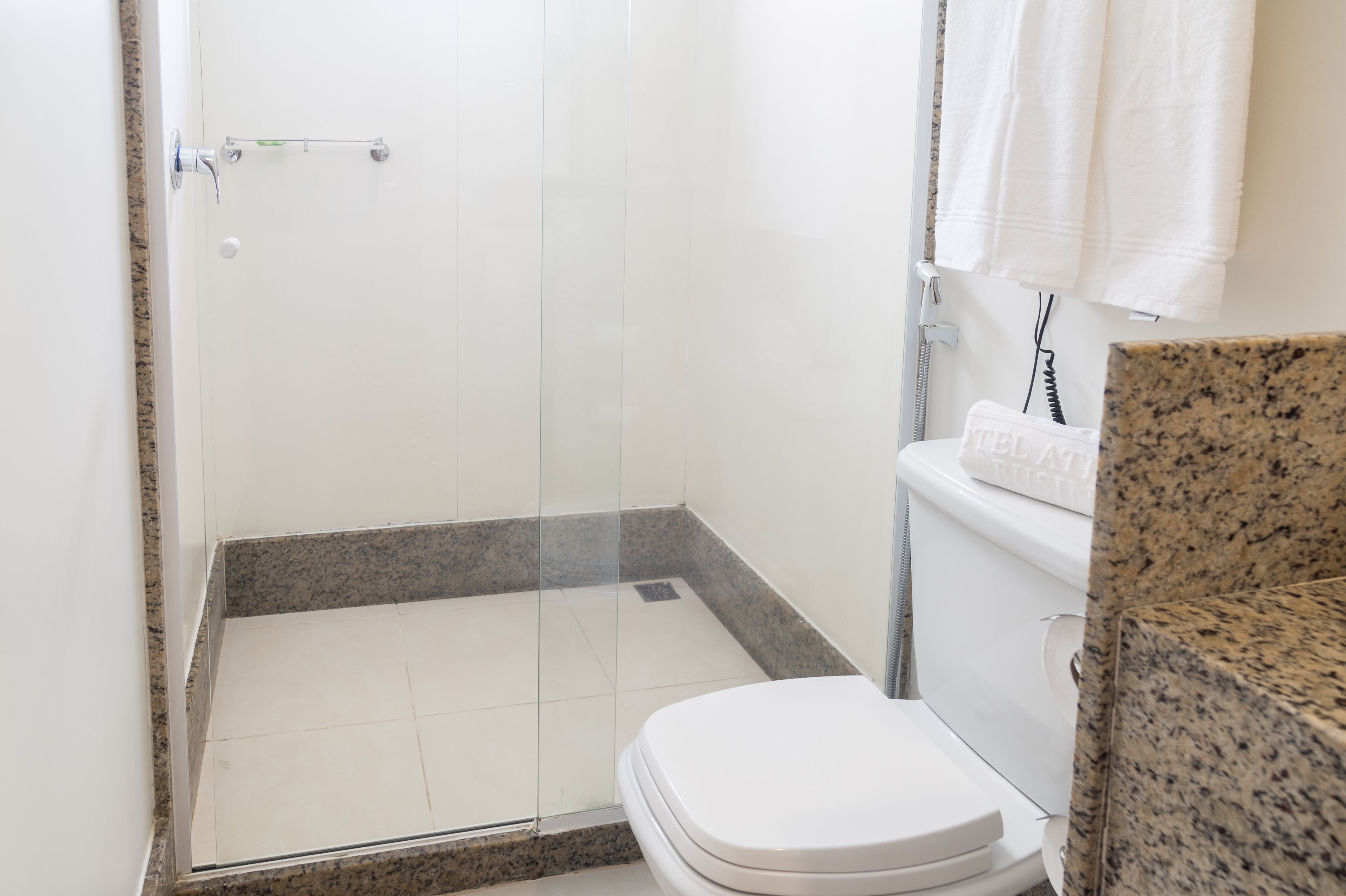 A bathroom with a shower, toilet, and granite countertop.