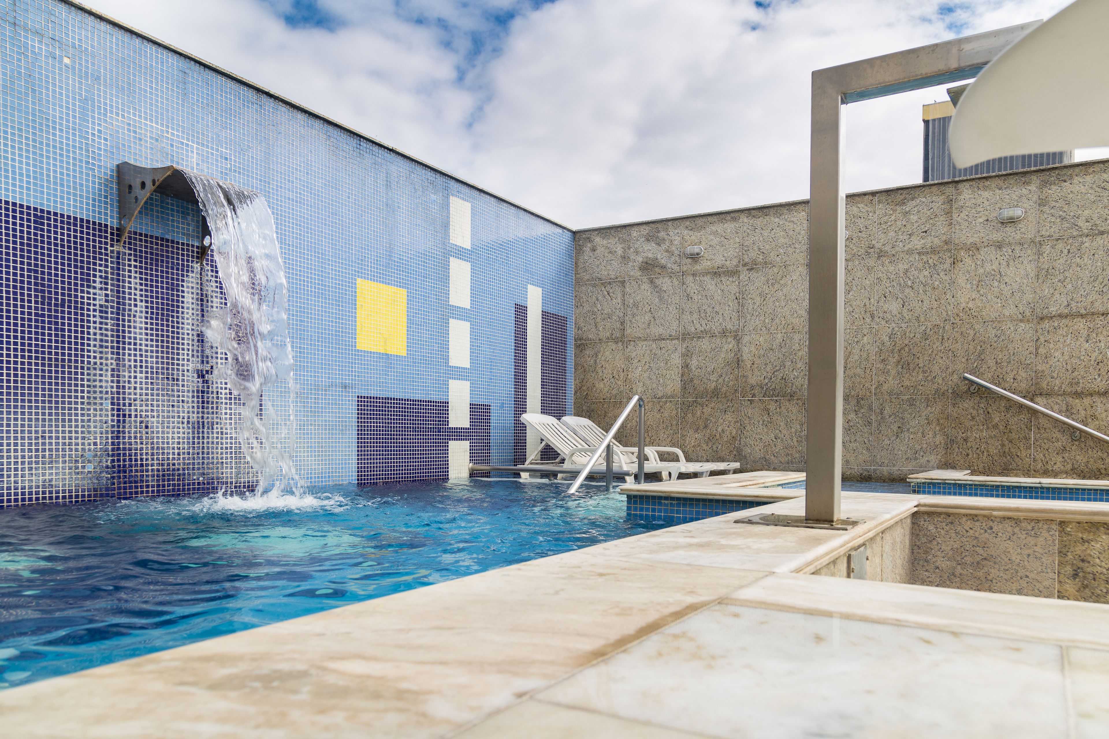 A swimming pool with a tiled wall and a concrete wall.