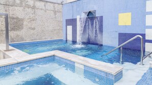 Une piscine agrémentée d’un élément décoratif aquatique, avec des murs carrelés et un escalier en métal.