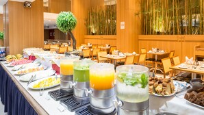 Un buffet proposant une variété de plats et de boissons, disposé dans un espace de restauration spacieux agrémenté de lambris en bois et d’une grande décoration en forme d’arbre.