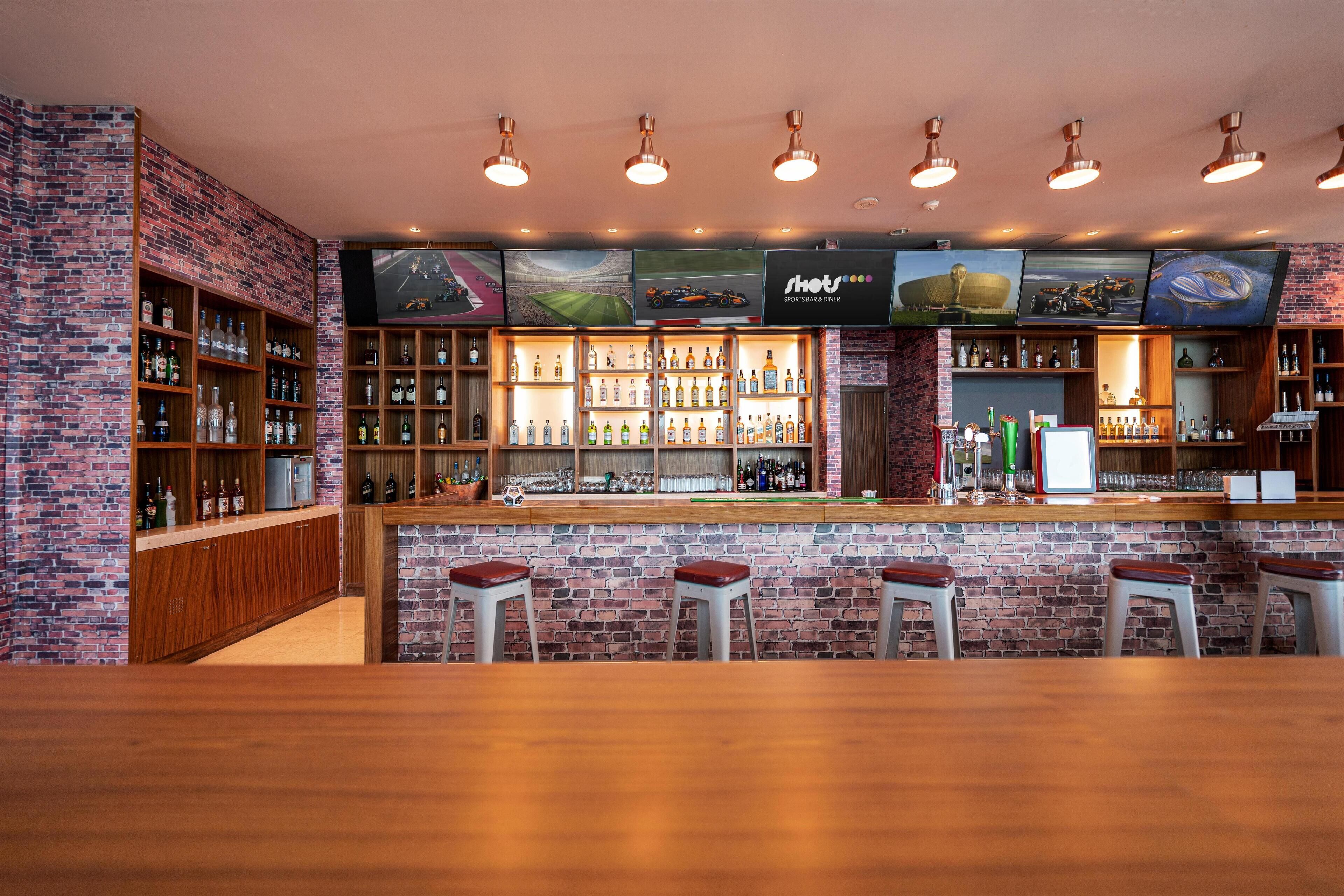 Eine Bar mit Backsteinwand, Holzböden mit Flaschen und Barhocker.