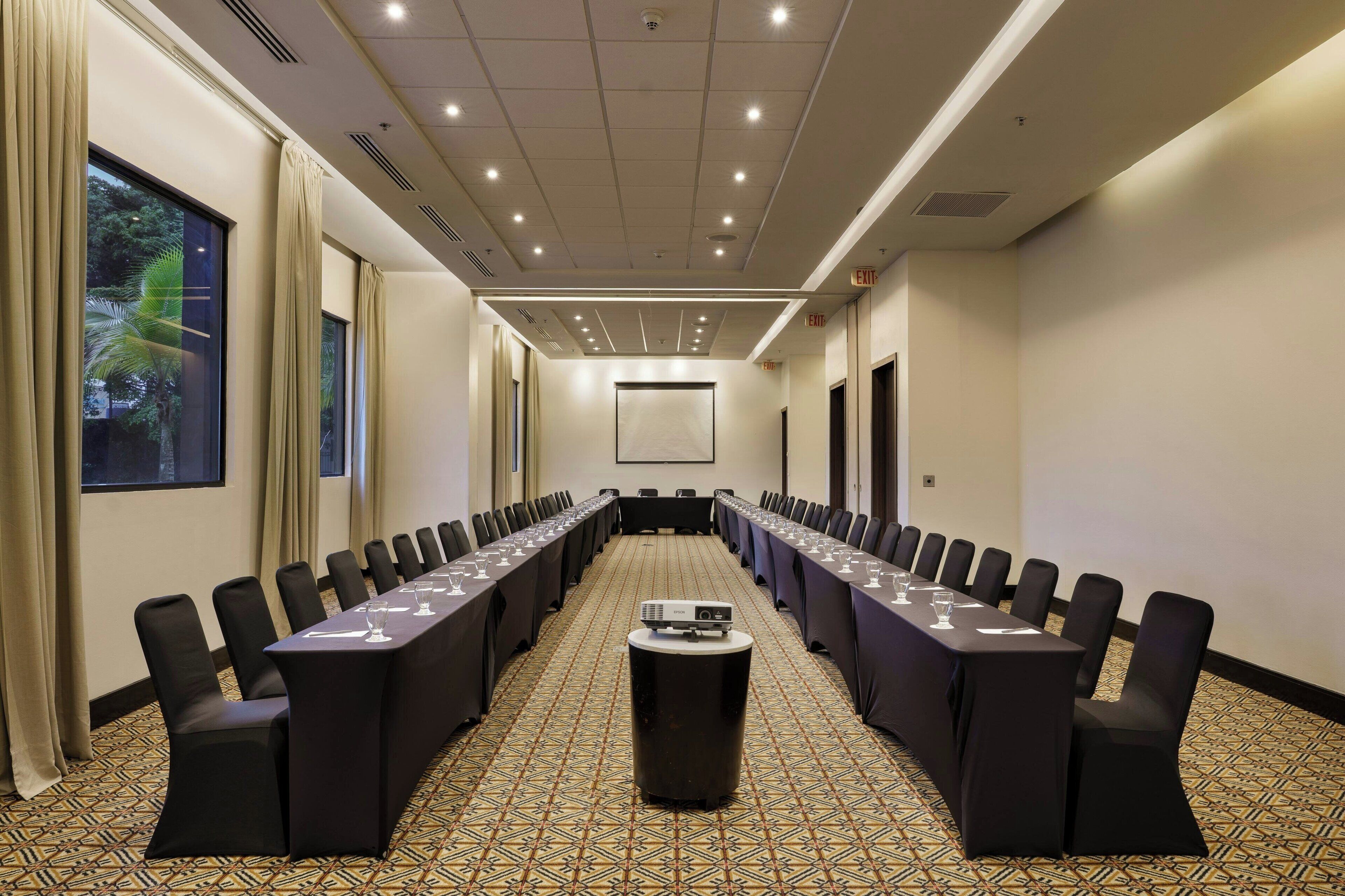 A conference room with a long table, black chairs, and a projector.