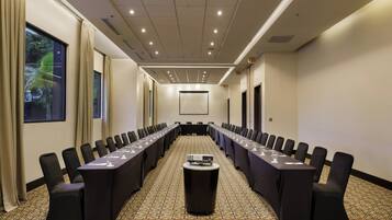A conference room with a long table, black chairs, and a projector.