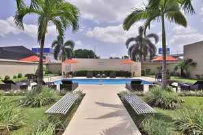 Una piscina al aire libre, sombrillas, sillones reclinables de piscina