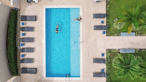 Vista aérea de una piscina rectangular con dos tumbonas y una escalera.