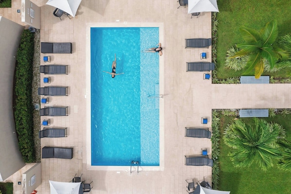 An aerial view of a rectangular swimming pool with two lounge chairs and a ladder.