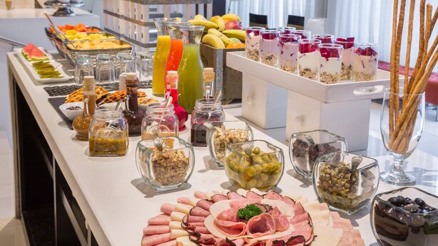 Un bufé con diversas opciones de comida, incluyendo frutas, jugos y quesos.