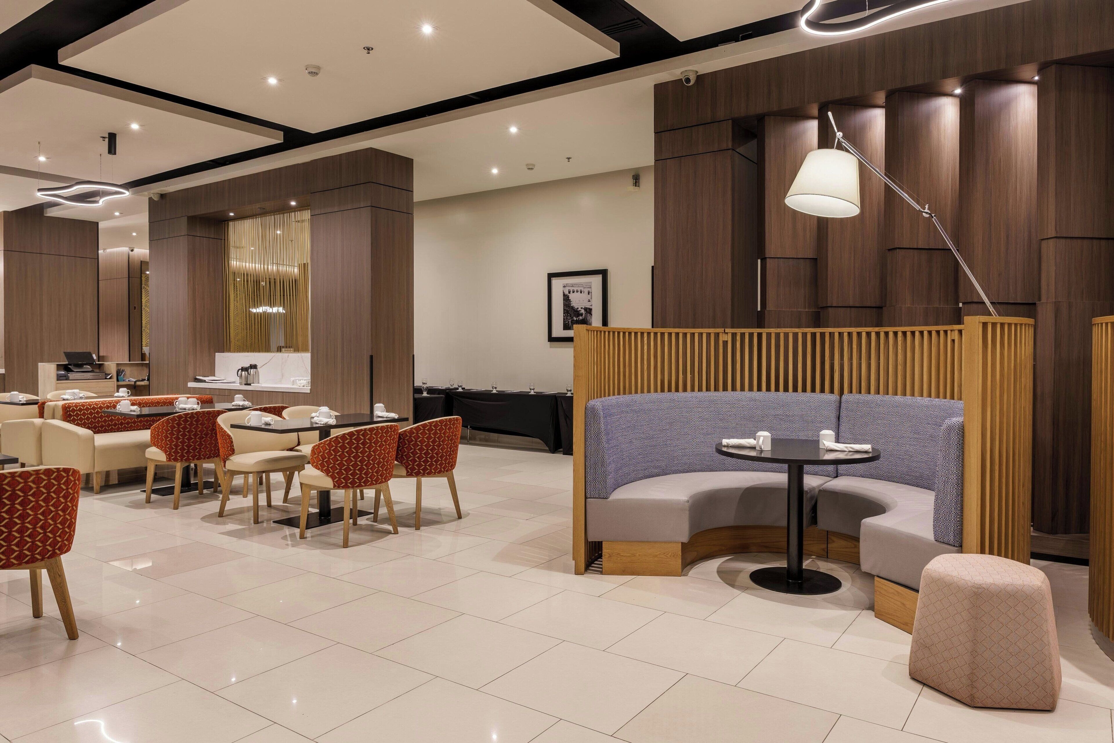Un hall d’hôtel moderne avec un comptoir d’accueil, un espace salon et une grande fenêtre.