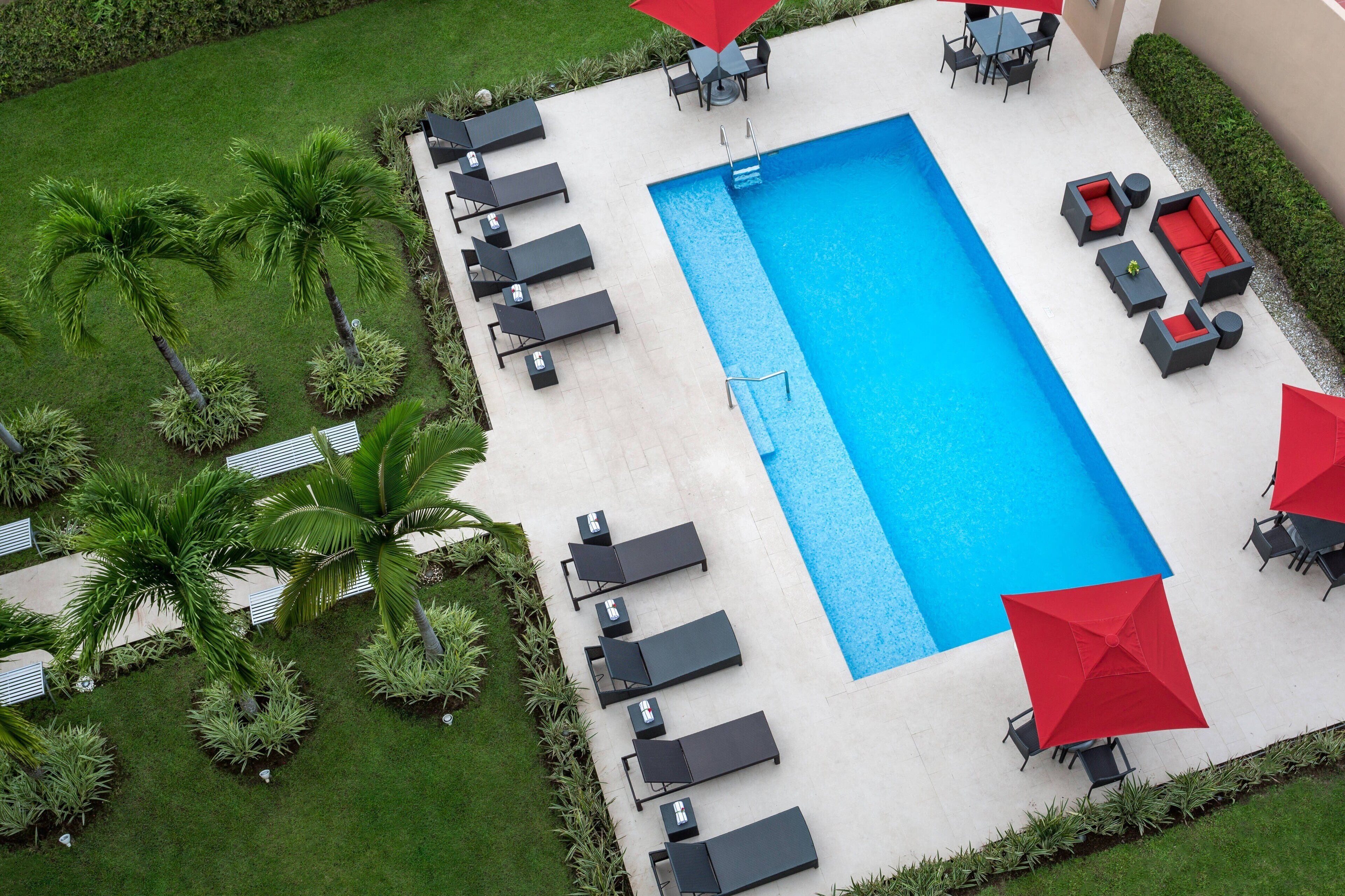 A rectangular swimming pool with lounge chairs and umbrellas around it.