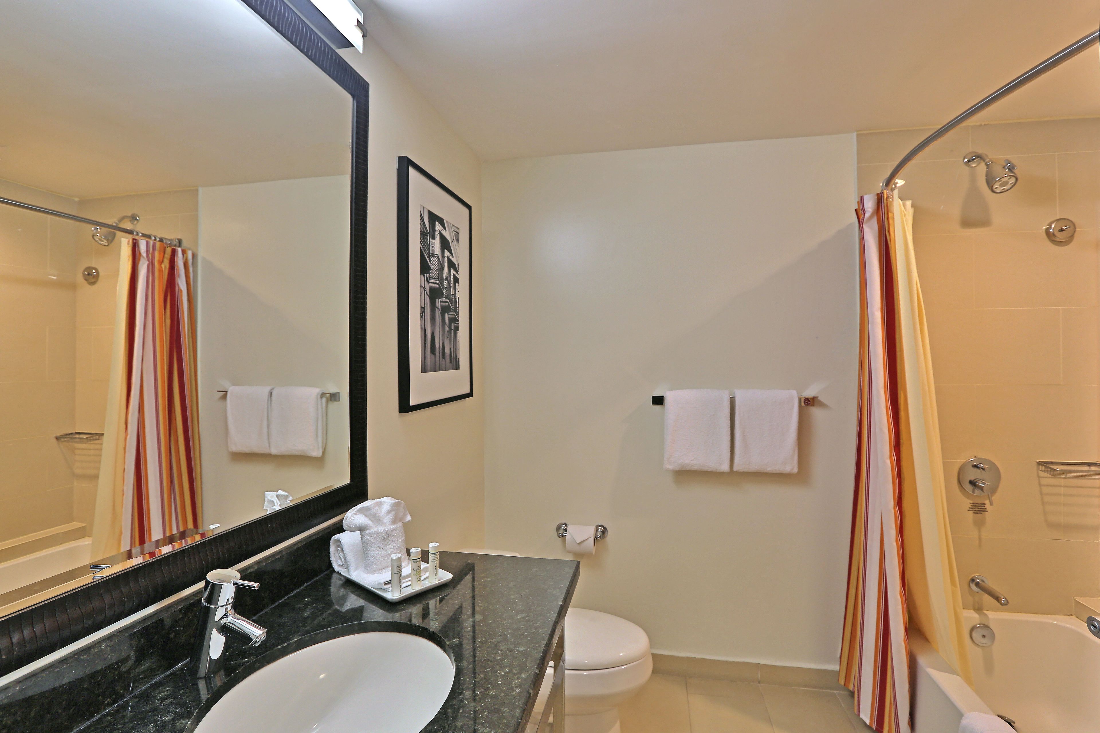 A modern bathroom with a large mirror, a sink, a toilet, and a shower area.