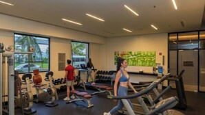 Un gimnasio con cintas de correr, máquinas de pesas y mancuernas.