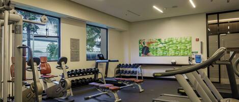 A gym with treadmills, weight machines, and dumbbells.
