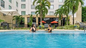 Una piscina al aire libre, sombrillas, tumbonas