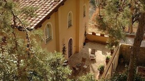 A yellow building with a tiled roof and arched windows. There is a patio with outdoor furniture and potted plants. - Country House La Locanda del Borgo (Pietralunga)