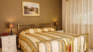 Un letto rifatto con una coperta a righe, un comodino con una lampada e un quadro appeso al muro.