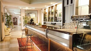 A bar area with stools, a counter, and shelves of liquor bottles. - Hotel San Marco (Alghero)