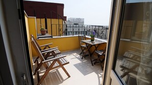 A balcony with wooden chairs and a table, a potted plant, and a view of buildings in the background. - Ahmet Efendi Evi (Istanbul)