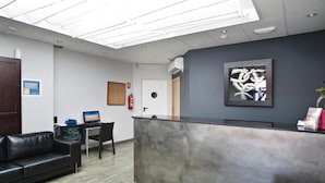 Un área de recepción con un mostrador moderno, un sofá de cuero negro y una recepción de color gris.