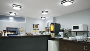 Una cocina moderna con refrigerador, microondas y cafetera.