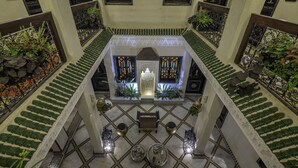 A grand atrium with a central seating area, ornate railings, and a tiled floor. - Riad Nesma Suites & SPA (Marrakech)