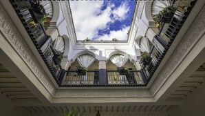 A courtyard with a central open space, ornate railings, and potted plants. - Riad Nesma Suites & SPA (Marrakech)