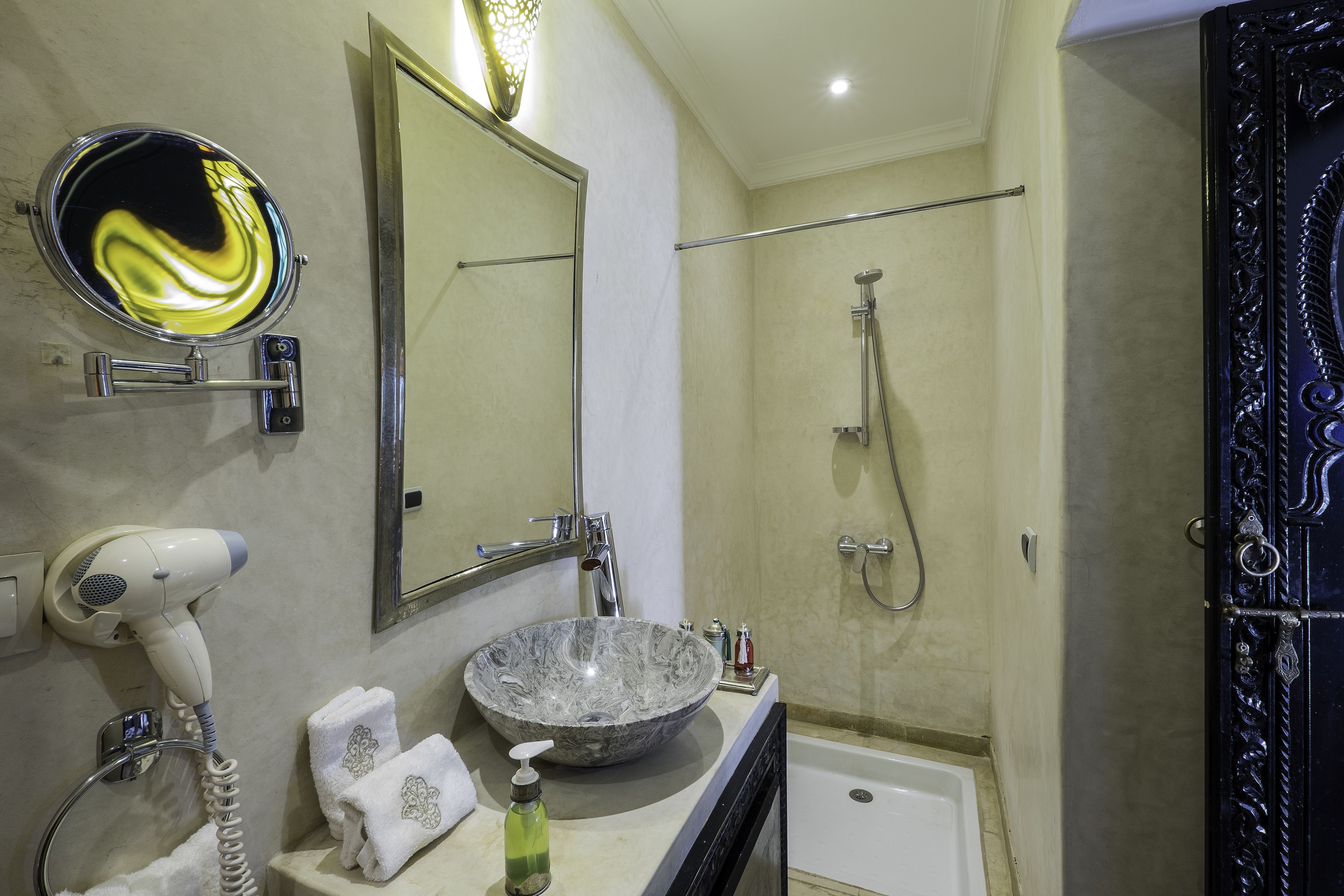 A bathroom with a round marble sink, a hairdryer, a towel rack, and a bathtub.