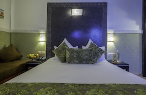 A hotel room with a large bed, decorative pillows, a fruit bowl, and two bedside lamps. - Riad Nesma Suites & SPA (Marrakech)