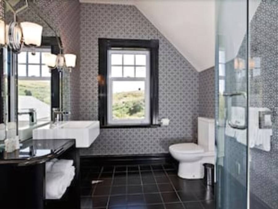 A modern bathroom with a large mirror, a sink, and a toilet.