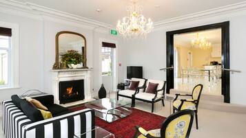 Uma sala de estar ampla com lareira, um candelabro e uma área de jantar com cadeiras e mesa.